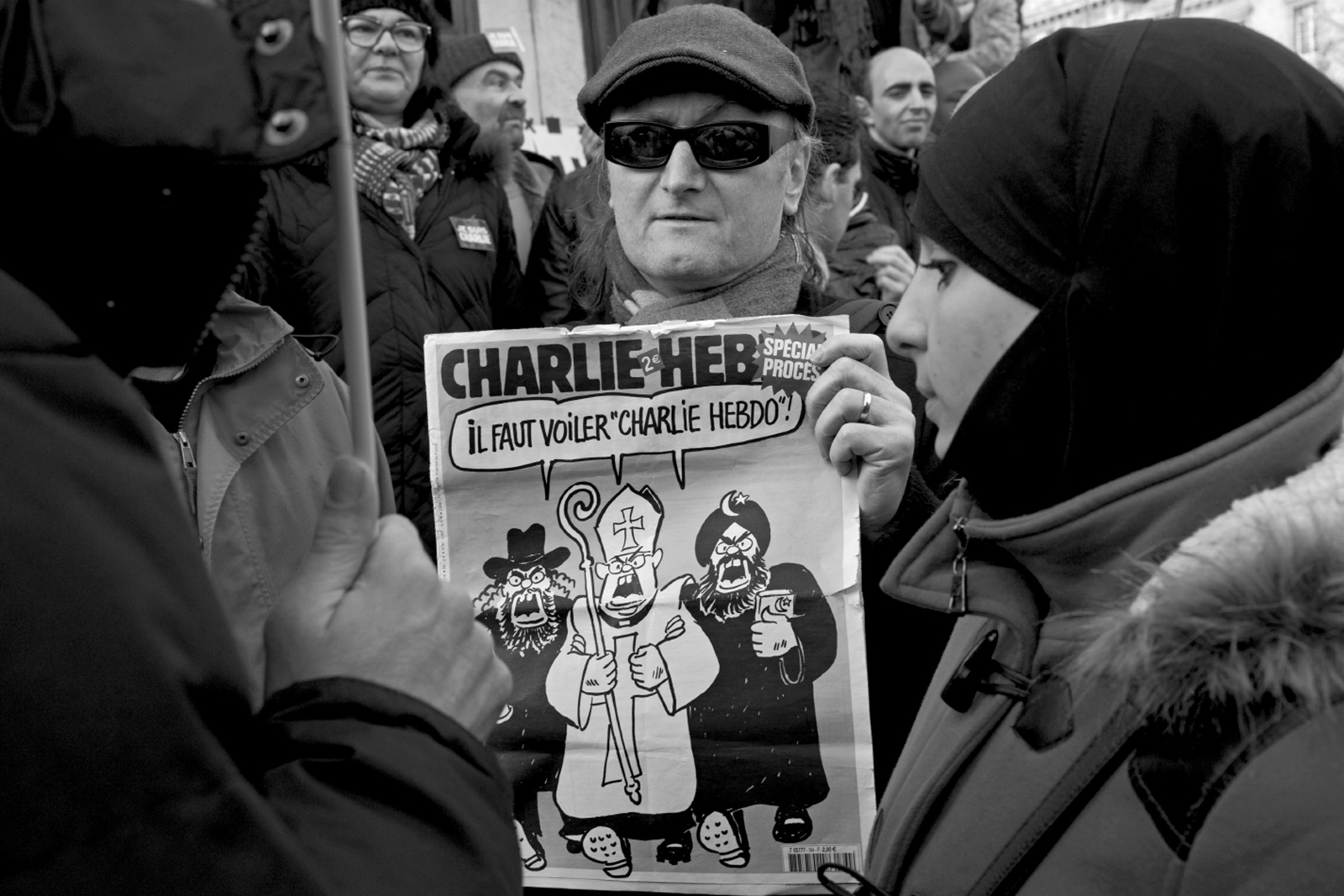 A demonstrator with an issue of Charlie Hebdo at the march against terrorism, Paris, January 11, 2015. The cartoon on the cover shows a Jew, a Catholic, and a Muslim demanding that ‘“Charlie Hebdo” must be veiled!’