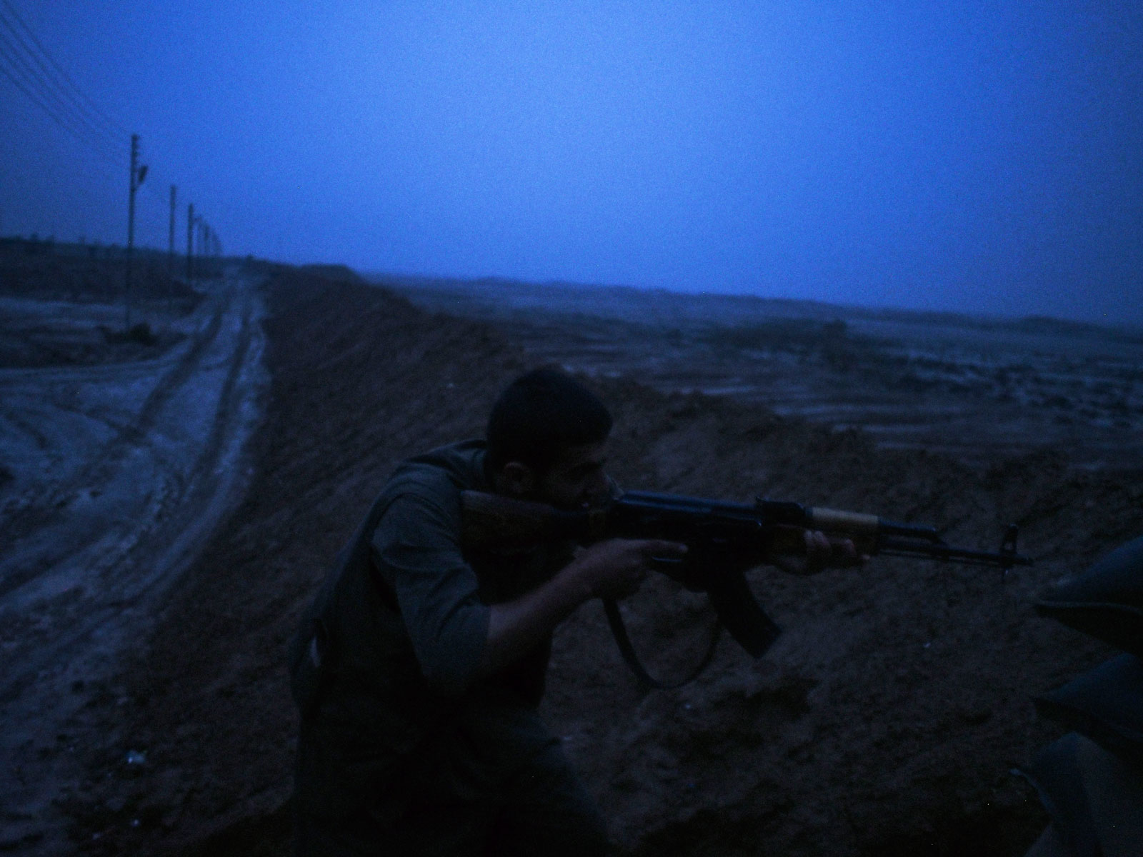 A Kurdish PKK fighter aiming his rifle at an Islamic State position, Dokuk, Iraq, December 3, 2014