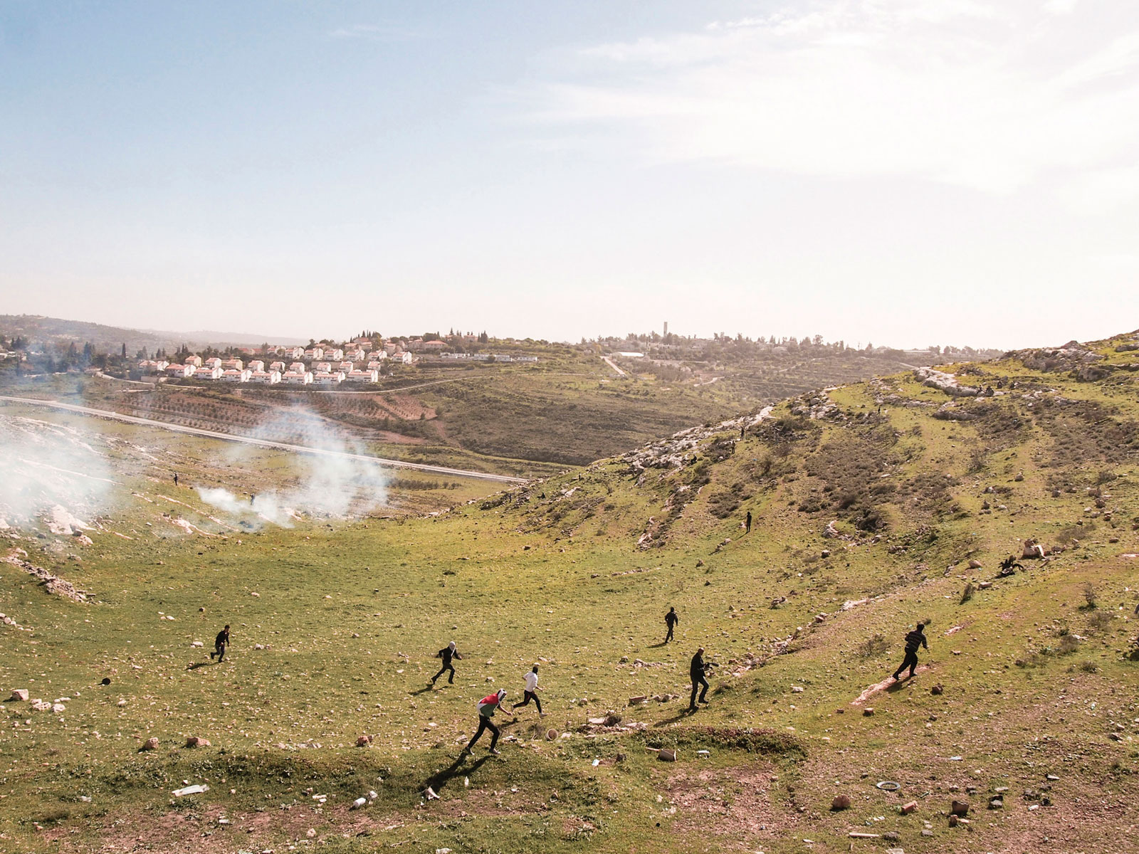 Palestinian protestors running from tear gas fired by Israeli soldiers at a weekly protest against the Israeli occupation, West Bank, Nabi Saleh, 2013