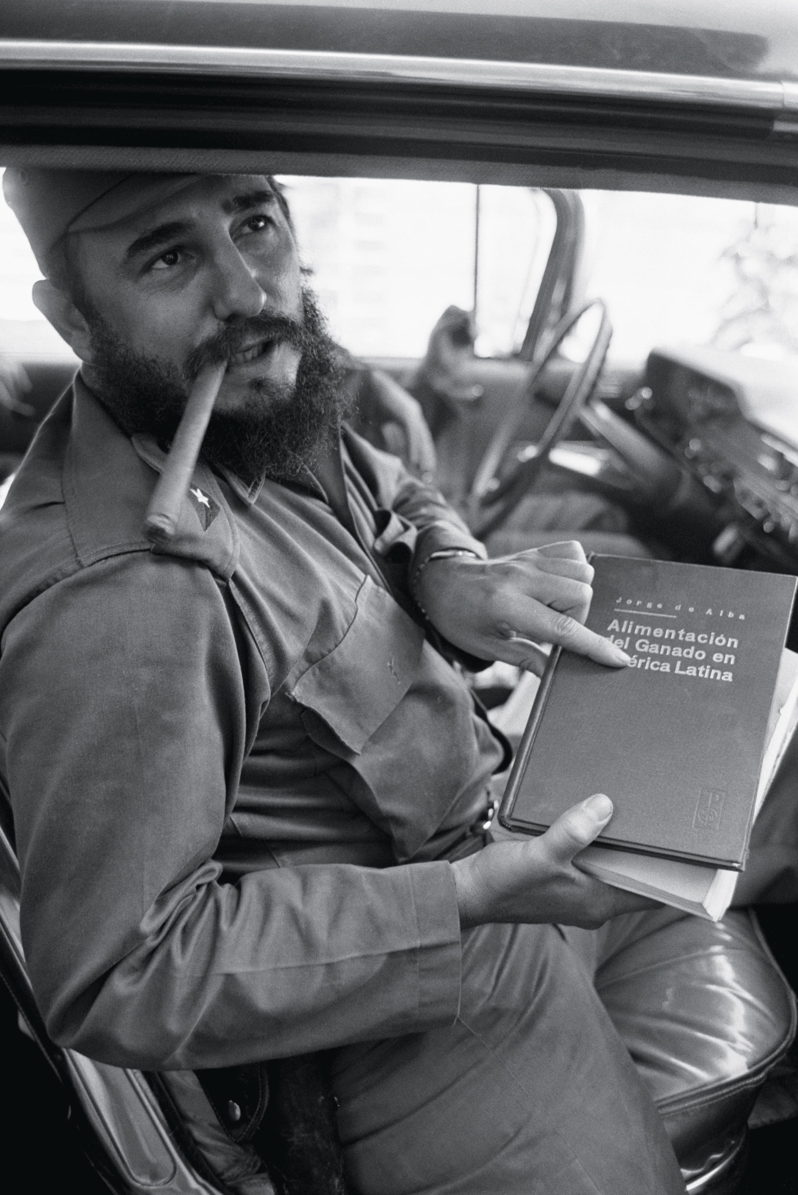 Fidel Castro holding <em>The Feeding of Cattle in Latin America</em>, by Mexican author Jorge de Alba, 1964