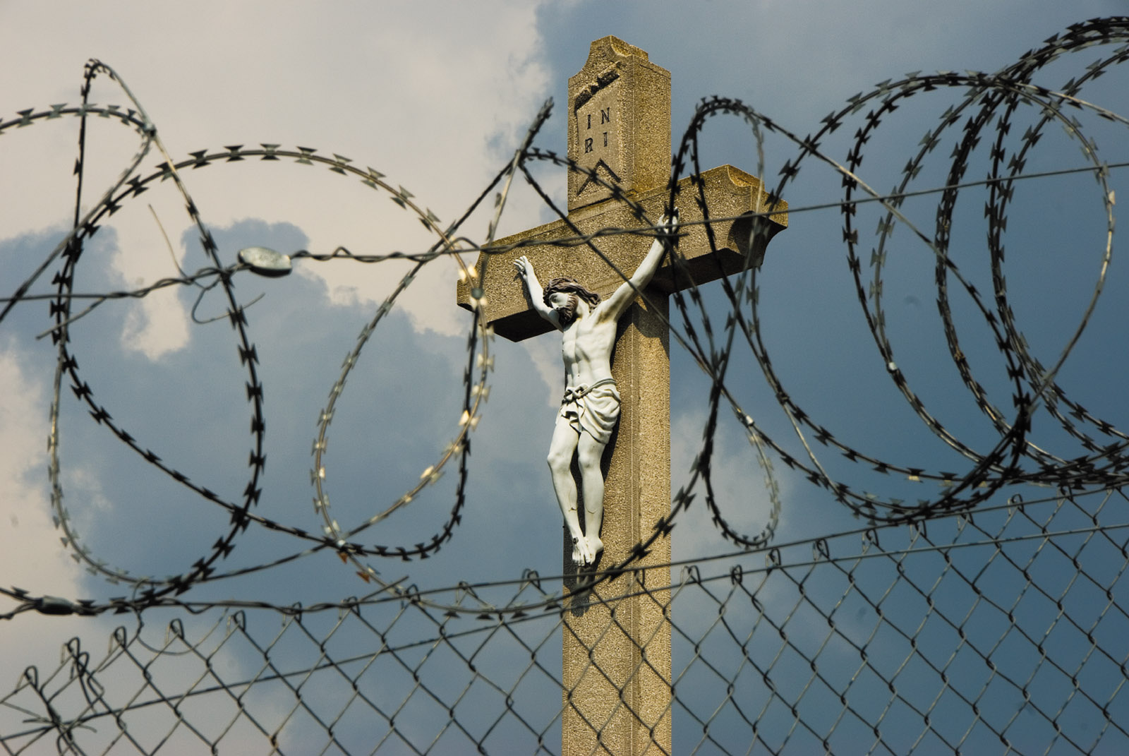 A Hungarian crucifix seen through the razor wire of the border fence, Rastina, Serbia, September 2016