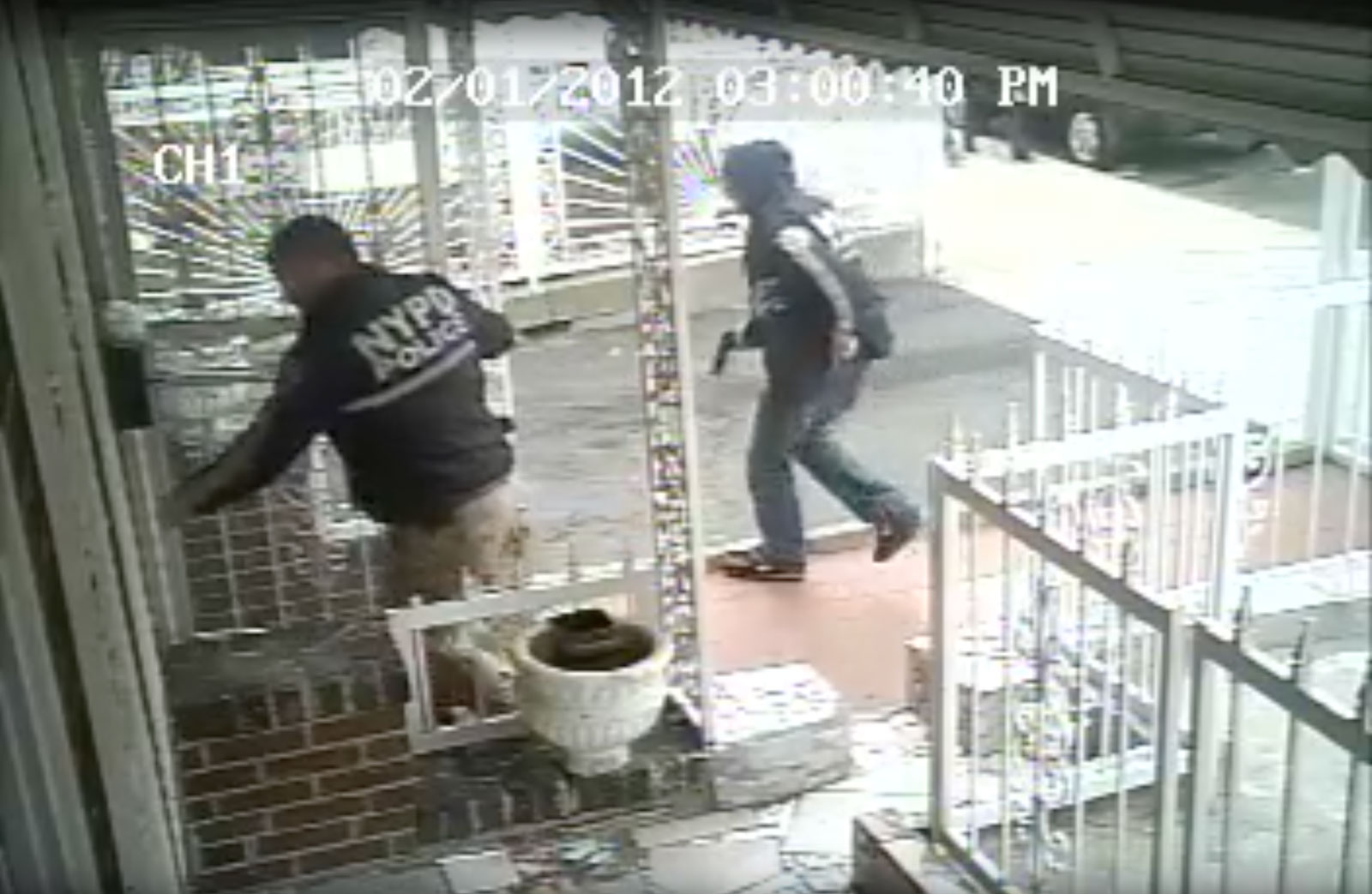 A still from the video surveillance footage taken outside Ramarley Graham's family home showing Officer Richard Haste trying to enter and another NYPD officer, gun drawn, February 2, 2012