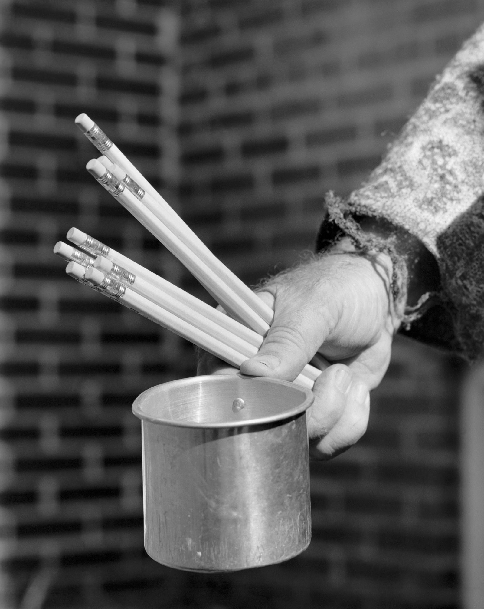 Close-up of a person's hand holding a mug and pencils