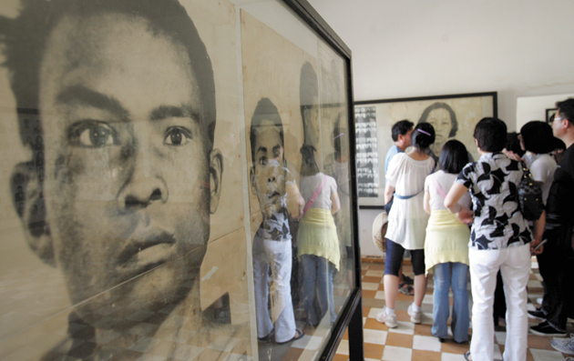 Tourists looking at photographs of Khmer Rouge victims at the Tuol Sleng Genocide Museum, Phnom Penh, Cambodia, February 13, 2009
