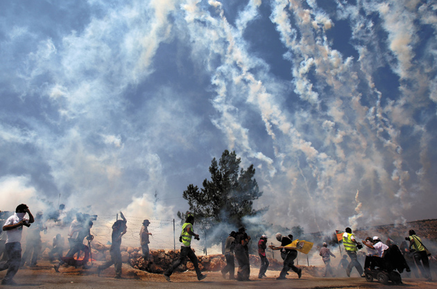 Protesters against the Israeli separation barrier fleeing a tear gas attack by Israeli soldiers in the West Bank village of Bil’in, July 10, 2009
