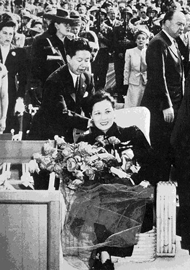 Madame Chiang at a celebration held in her honor at the Hollywood Bowl, April 4, 1943. The flowers she is holding were given to her by Mary Pickford, who can be seen in the background on the right. 
