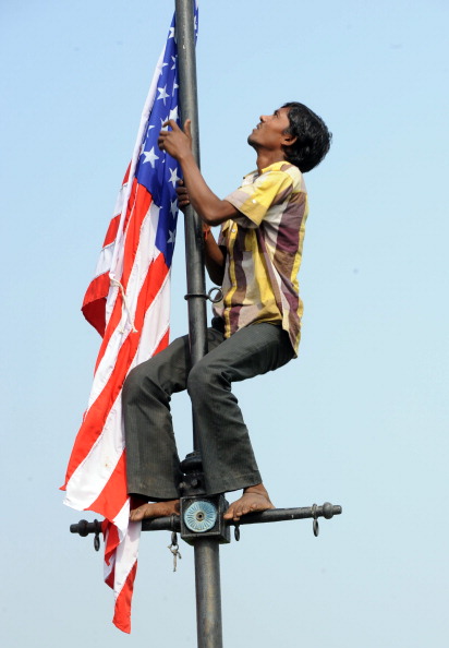 A worker removes the US and Indian national flags after the departure of US President Barack Obama and his wife Michelle from New Delhi, November 9, 2010