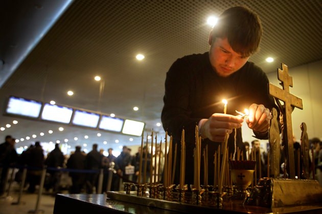 A clergyman lighting candles at the site of a bombing at Domodedovo Airport, January 26, 2011