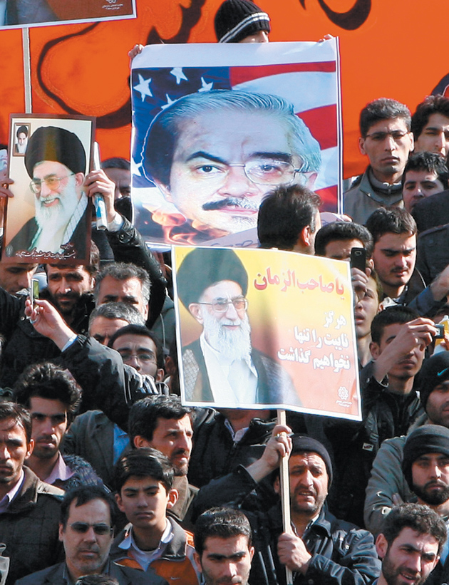 Iranian government supporters carrying posters of opposition leader Mir Hossein Moussavi (depicted in front of an American flag to imply that he is supported by the US) and Supreme Leader Ali Khamenei at a demonstration in Tehran, February 18, 2011
