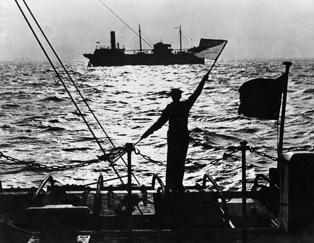 A British sailor signaling a merchant ship as it passes the naval control base in the Thames estuary, November 1939
