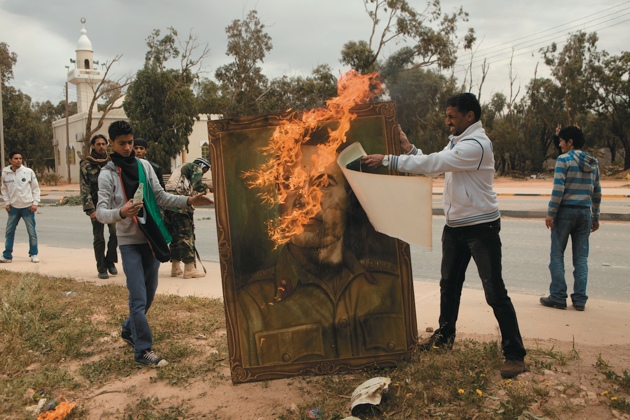 Young men burning a portrait of Muammar Qaddafi, Benghazi, Libya, March 21, 2011