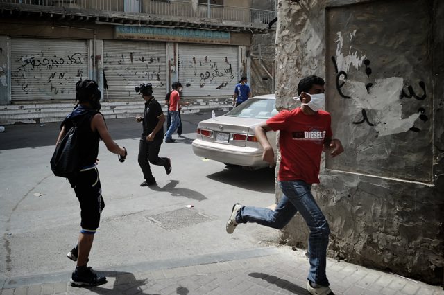 Bahraini youths run for cover as police fire teargas during Labor Day protests in the Manama suburb of Sanabis, May 1, 2012