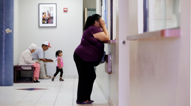 A woman stands at the registration window at Nuestra Clinica Del Valle in San Juan, Texas, July 12, 2012. About 85 percent of those served at the clinic are uninsured. The Texas Hospital Association estimates that care for uninsured patients cost hospitals in the state $4.5 billion in 2010.