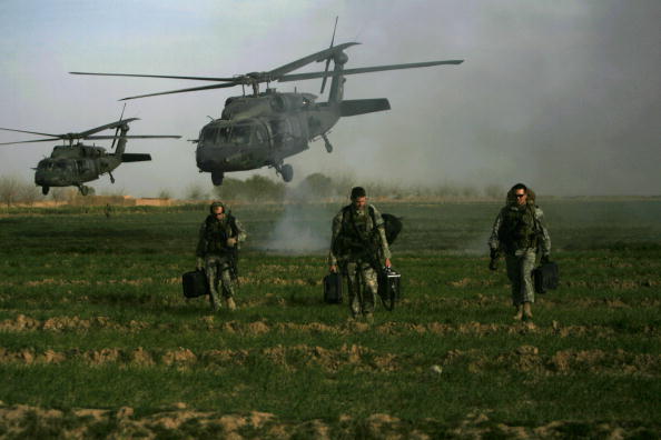 US army special forces walk in a field as Blackhawk helicopters transporting NATO officers land in Marjah's Balakino Bazar neighborhood on February 24, 2010.