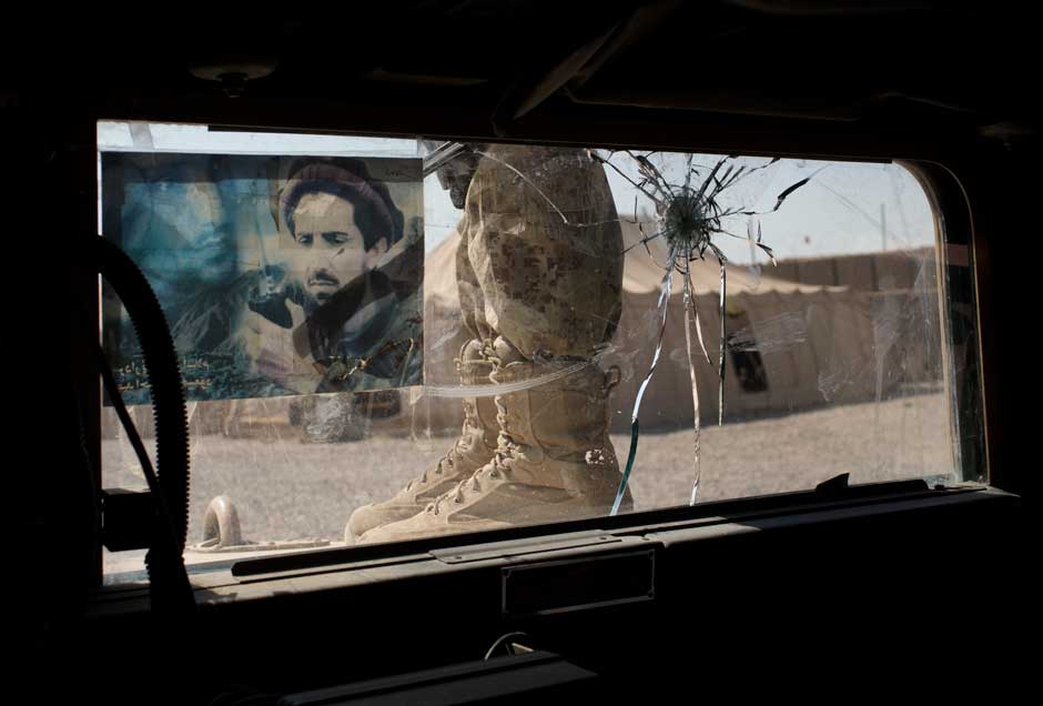 An Afghan officer after a patrol in Helmand Province, Afghanistan; the image on his vehicle's windshield depicts anti-Taliban warrior Ahmed Shah Masood, October 19, 2012