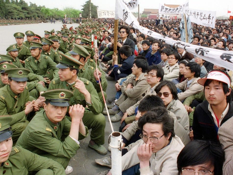 Pro-democracy student protesters sit face to face with policemen outside the Great Hall of the People in Tiananmen Square, Beijing, April 22, 1989