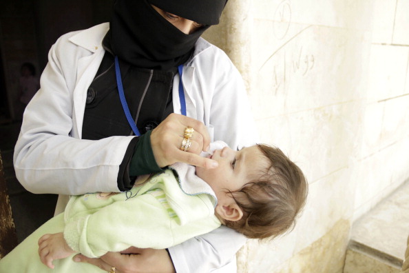 A health worker giving polio vaccine drops to a child, as part of a vaccination campaign organized by the opposition Assistance Coordination Unit, Aleppo, Syria, May 5, 2014