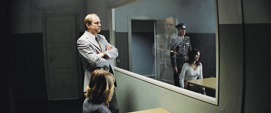 A Stasi official observing the interrogation of the lover of an East German playwright whose loyalty to the state is questioned, in Florian Henckel von Donnersmarck’s film The Lives of Others, 2006