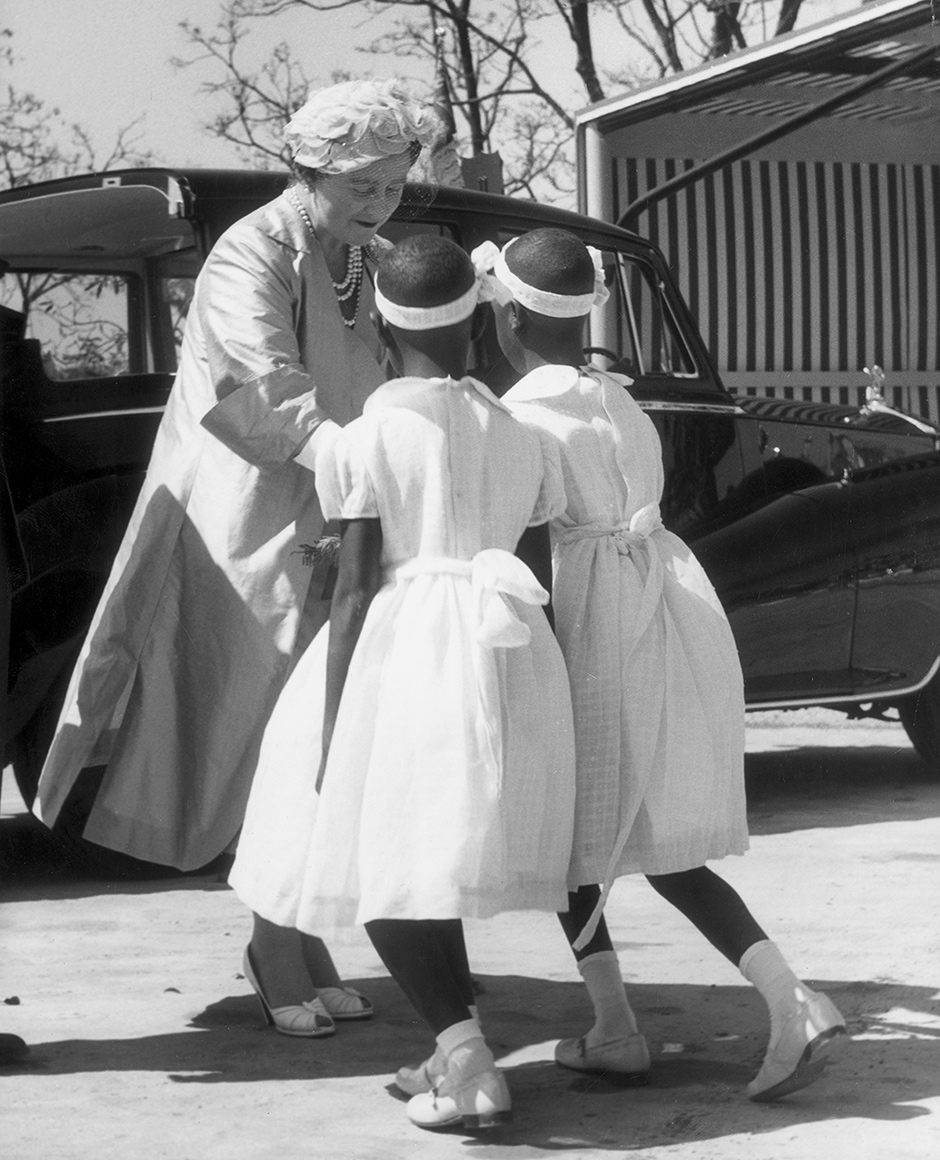 Queen Elizabeth the Queen Mother receiving flowers from local twin girls during a visit to Northern Rhodesia’s copper belt, 1957