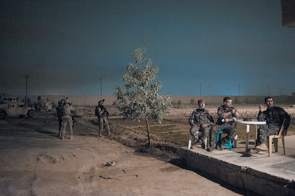 Iraqi policemen and American soldiers waiting while their commanders plan a joint patrol of southern Baghdad, 2010; photograph by Peter van Agtmael from his book Disco Night Sept. 11, published by Red Hook Editions