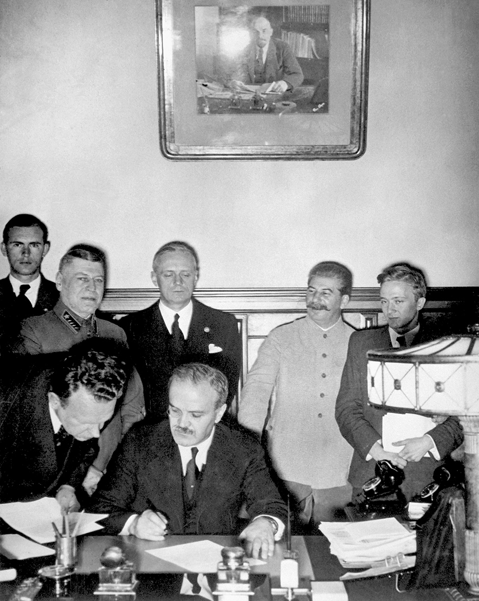 Soviet Foreign Minister Vyacheslav Molotov signing the Nazi–Soviet Pact, with German Foreign Minister Joachim von Ribbentrop directly behind him, next to Stalin, August 23, 1939