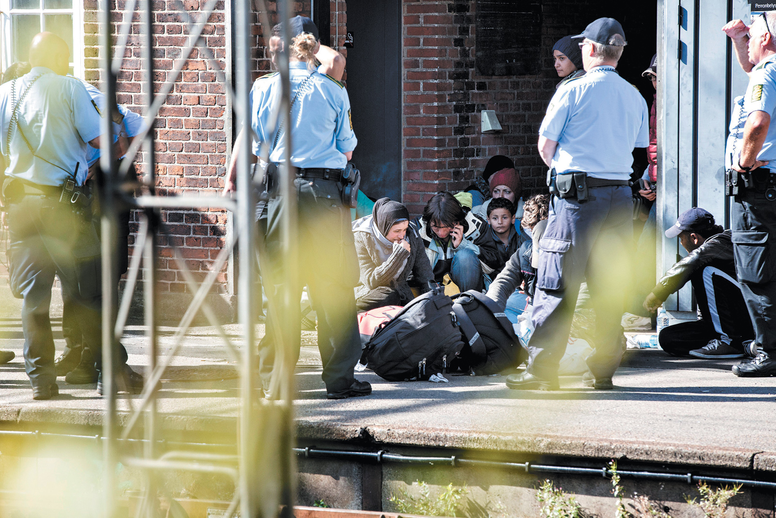 Police officers guarding refugees at Padborg Station, Denmark, after they entered the country from Germany, September 2015