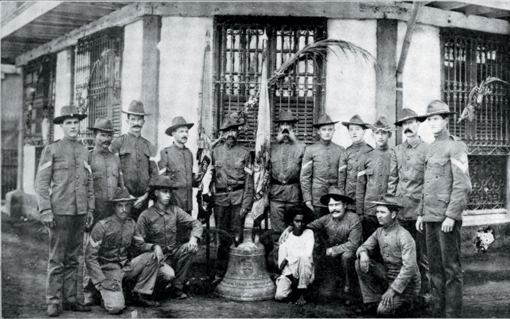 US soldiers who survived a surprise attack during the Philippine-American war posing with one of the bells of Balangiga, Philippines, 1901-1909