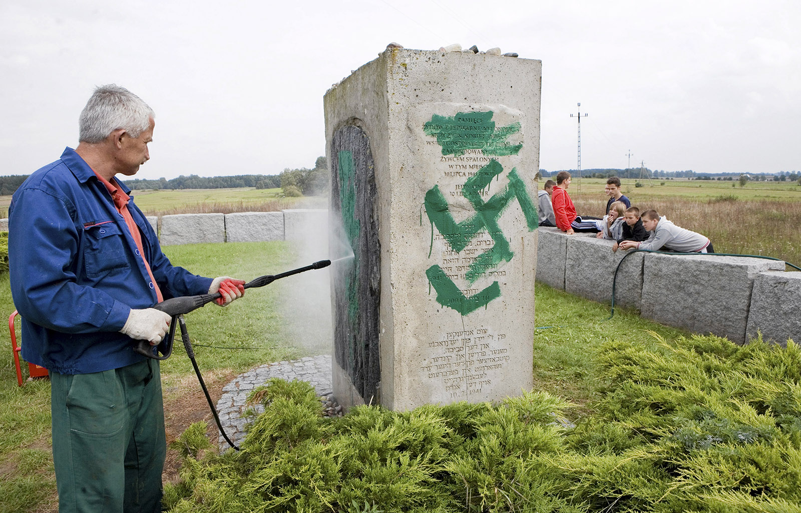 A worker cleaning a monument to the victims of the 1941 Jedwabne pogrom after it was defaced by neo-Nazis, Poland, 2011