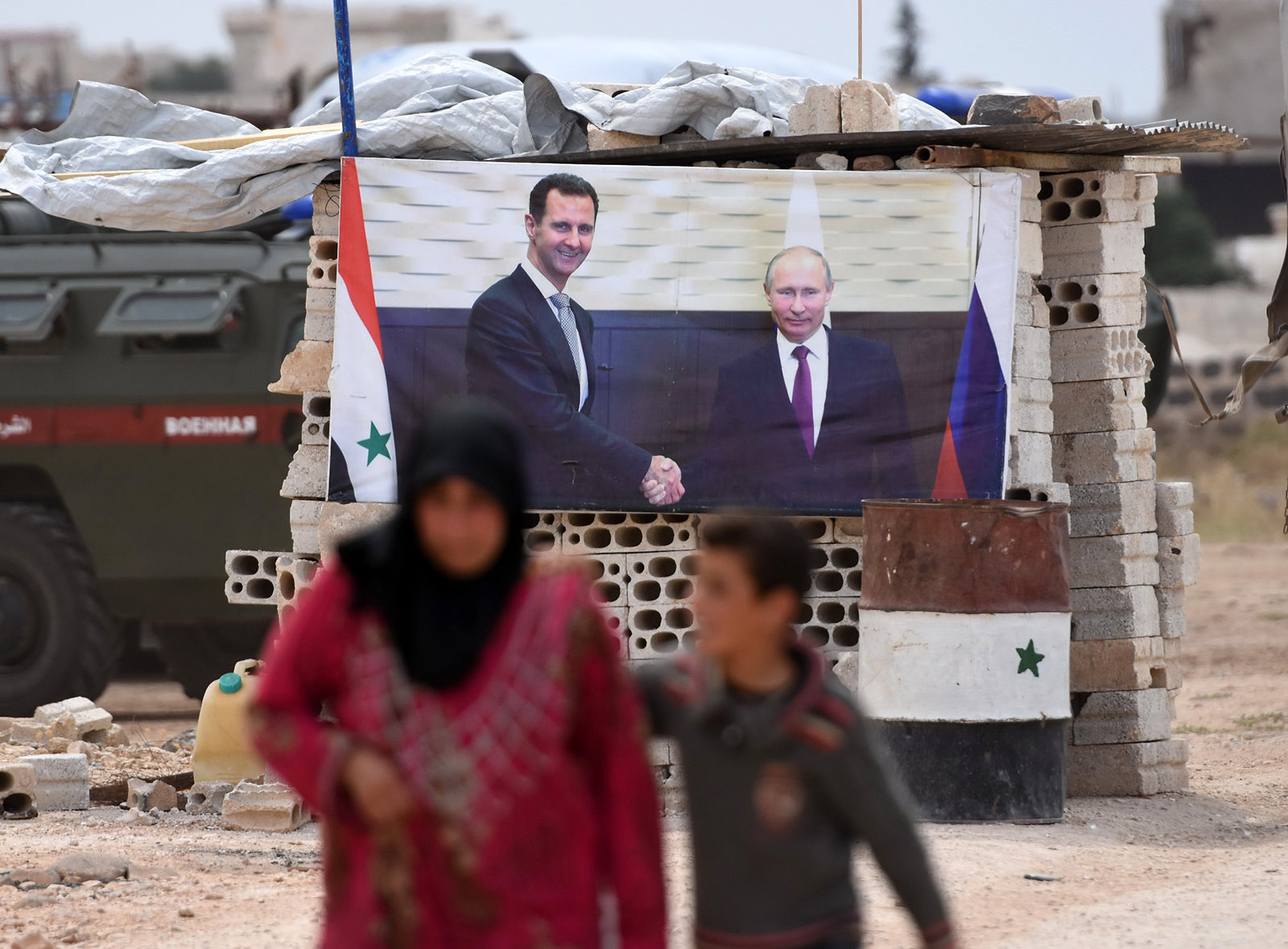 A Syrian woman and boy walking past a Syrian government checkpoint in western Idlib province, June 1, 2018