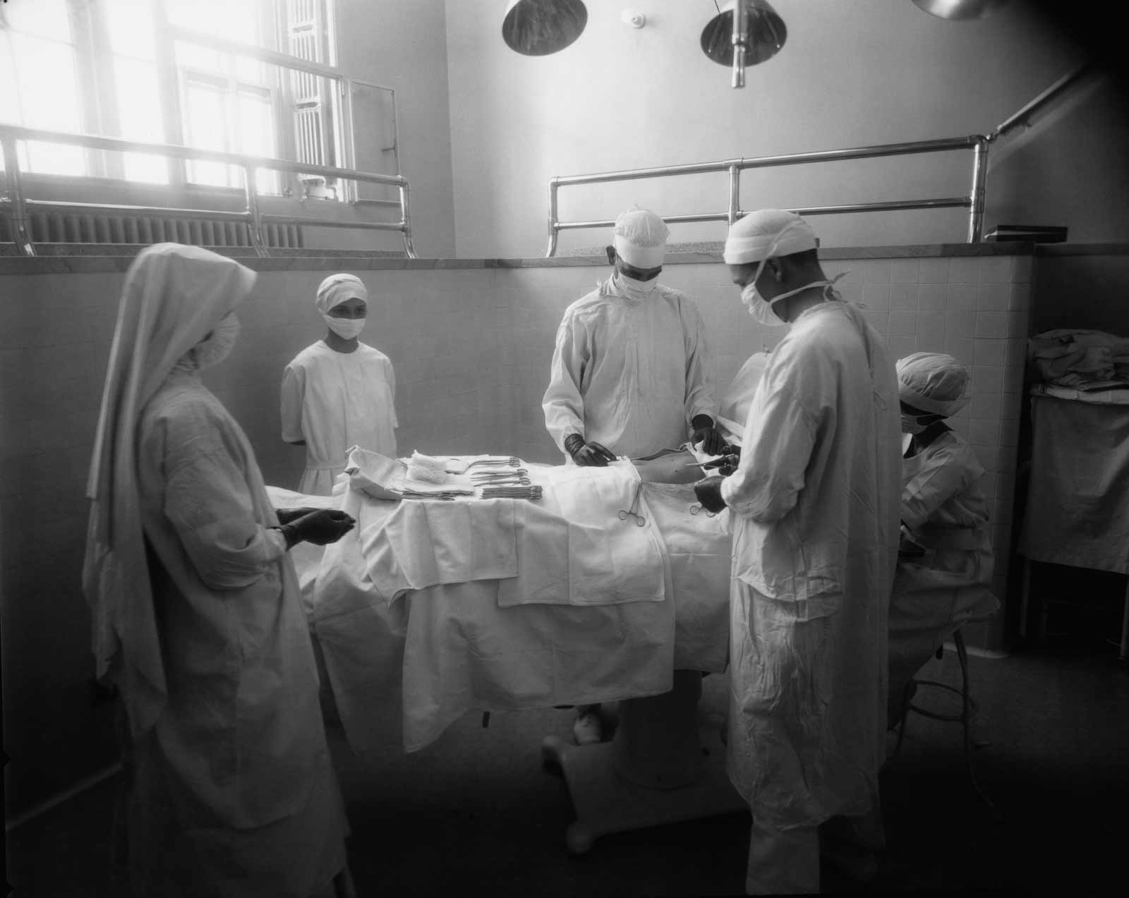 A still from Ken Burns's The Mayo Clinic: Faith—Hope—Science (2018), showing an operation at the Mayo Clinic with an assisting nun trained as a nurse, 1923