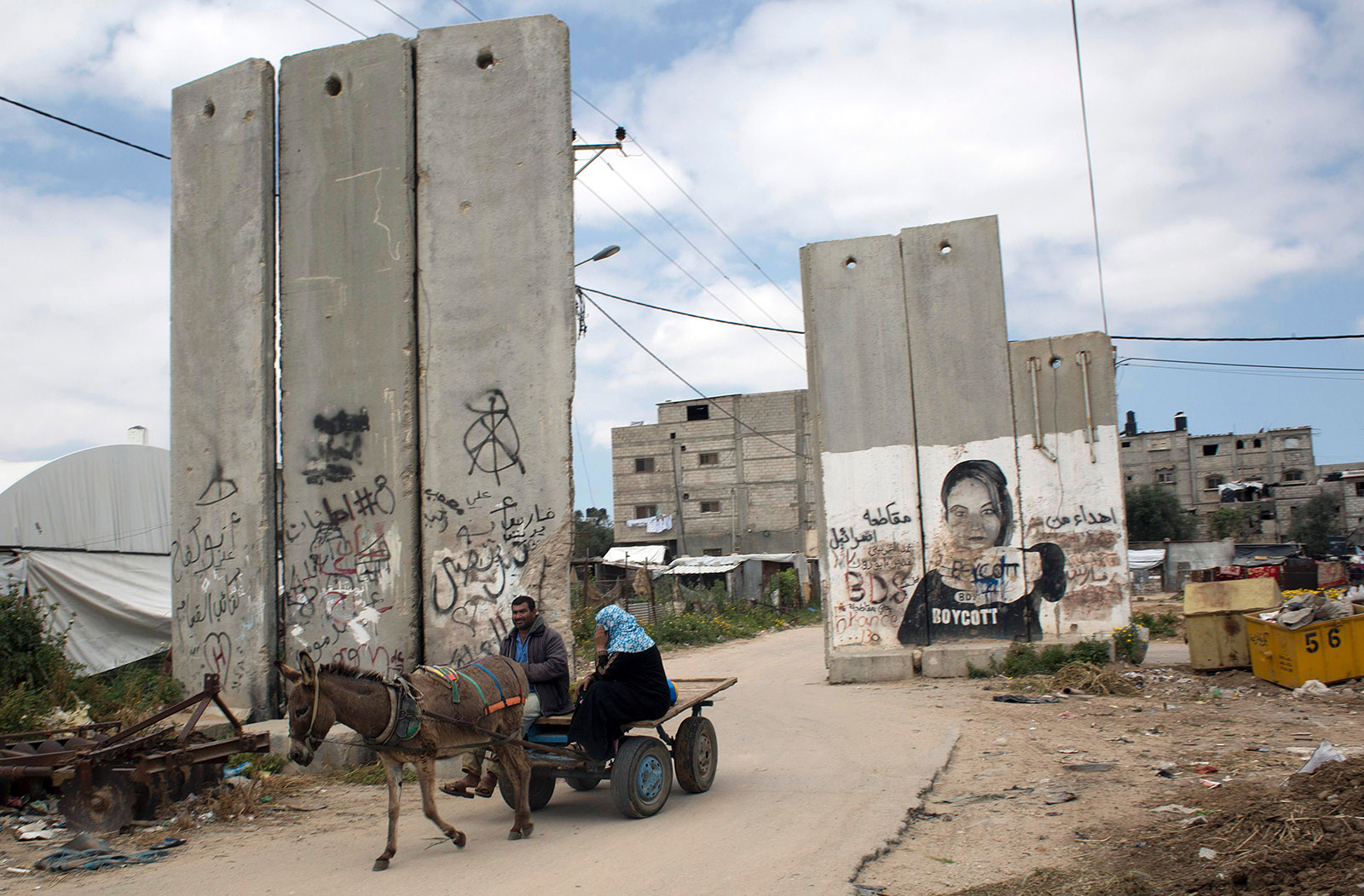 Palestinians riding a donkey-drawn cart past a mural calling for a boycott of Israel, Khan Yunis, Gaza Strip, 2016