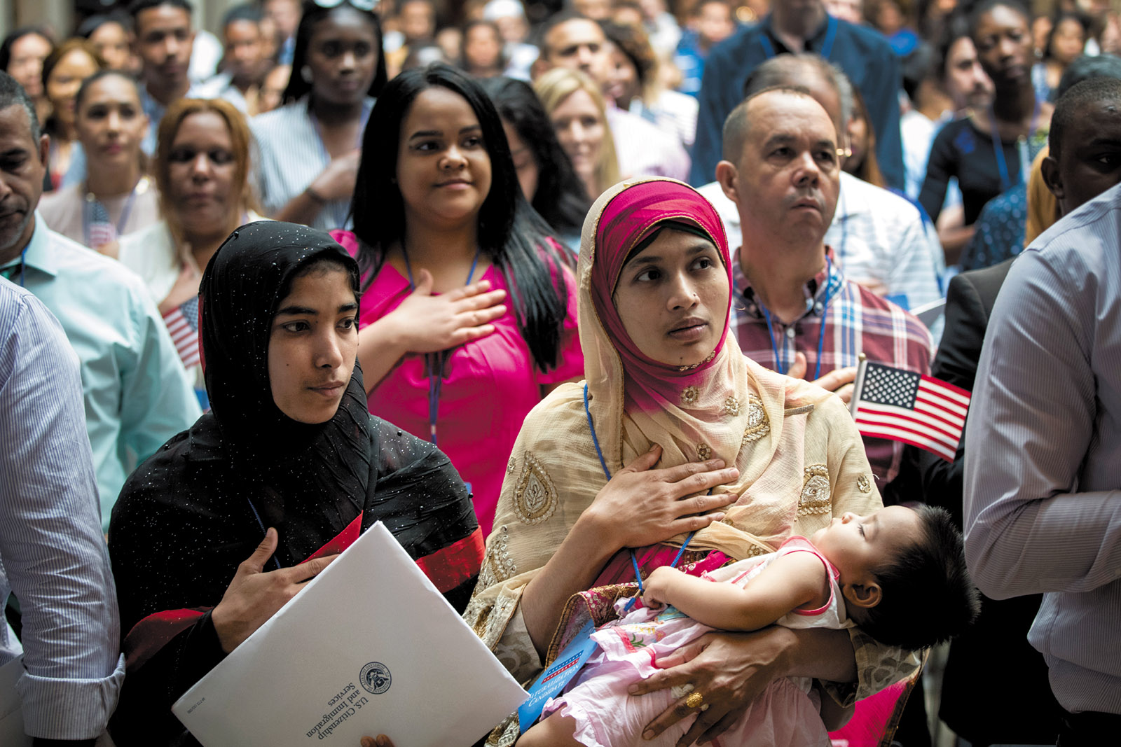 Mosammat Rasheda Akter (center), originally from Bangladesh, reciting the Pledge of Allegiance while holding her daughter after becoming a US citizen during a naturalization ceremony at the New York Public Library, July 2018