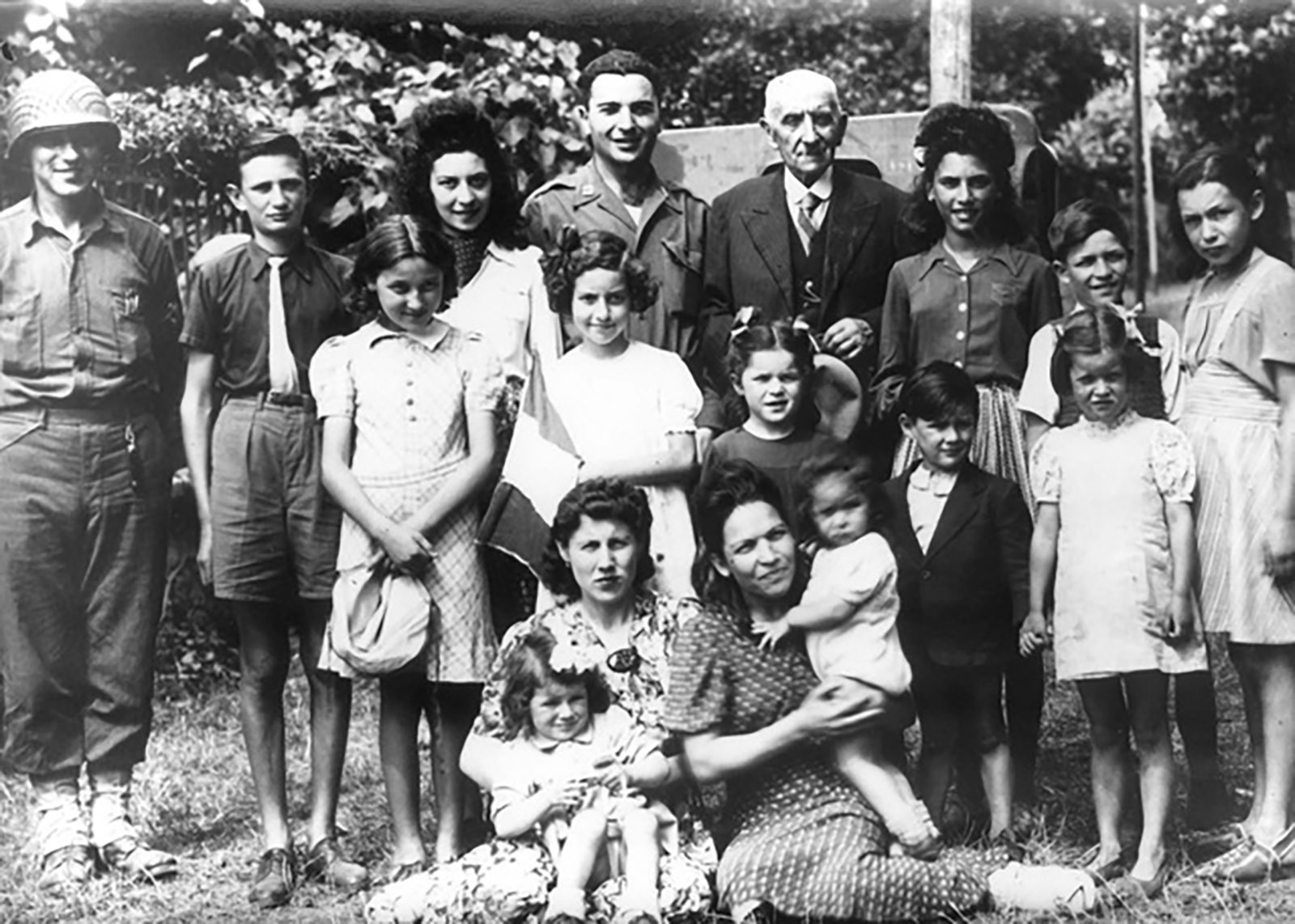 The elderly Aristide Gasnier, mayor of Vibraye, with two US soldiers and some of the Jewish refugees he helped save during the Nazi occupation; Huguette stands directly in front of Gasnier; her older brother Maurice is the boy at the far right. Sarthe, France, 1944