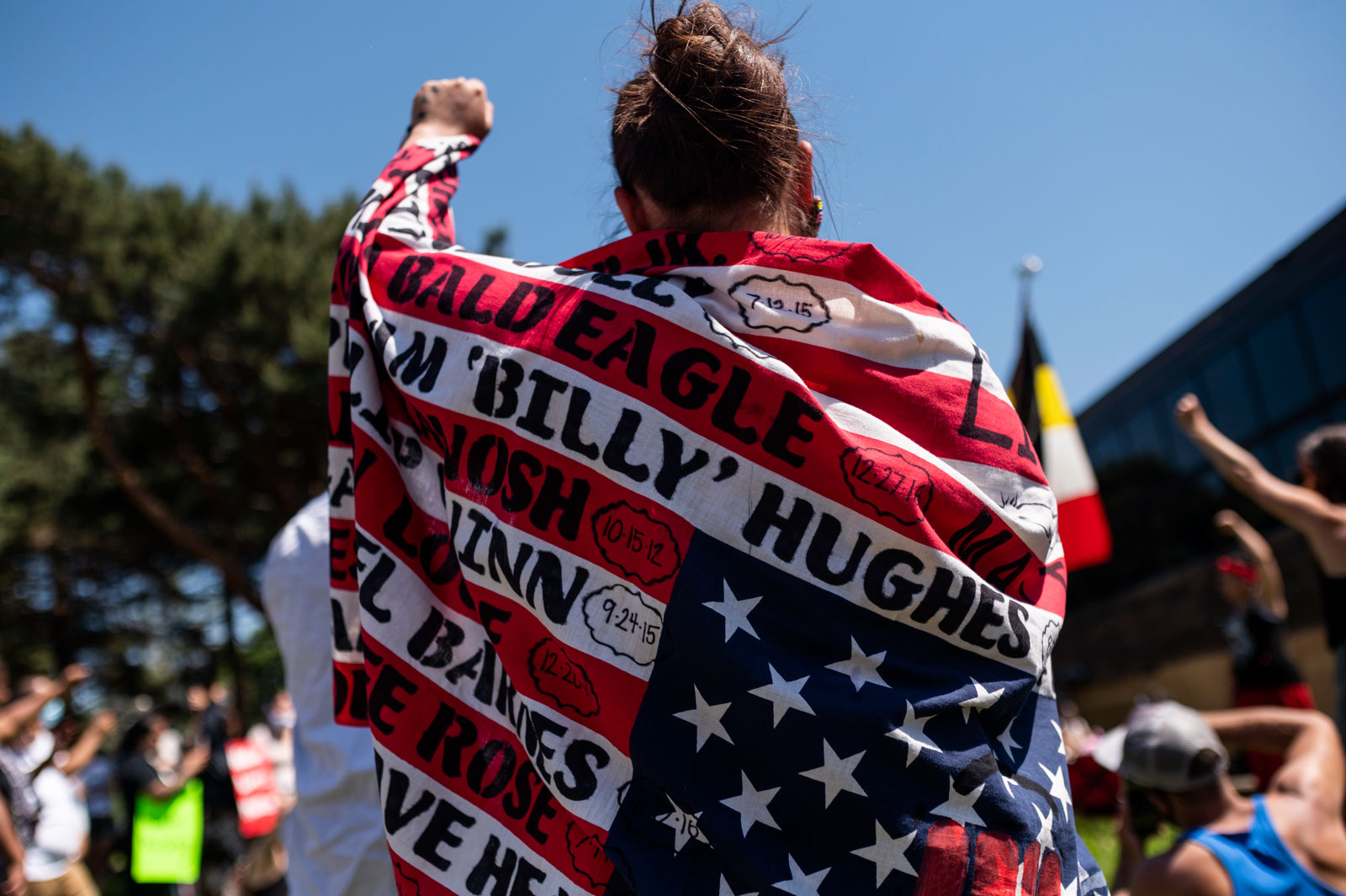 A woman draped in a flag with the names of Native American people who have been killed, at a demonstration outside the American Indian Center, Minneapolis, Minnesota, June 7, 2020