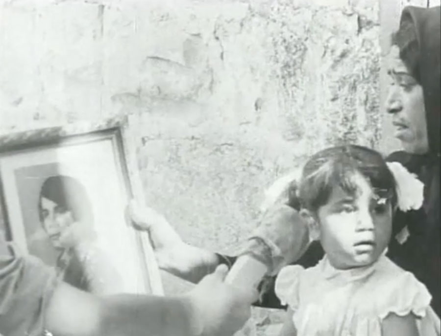 A still showing a girl and a woman in front of a framed picture, from Mustafa Abu Ali’s film They Do Not Exist, 1974