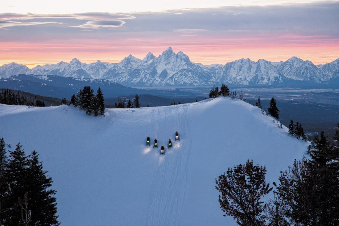 Snowmobilers on Angle Mountain with the Teton Range in the background, Togwotee, Wyoming