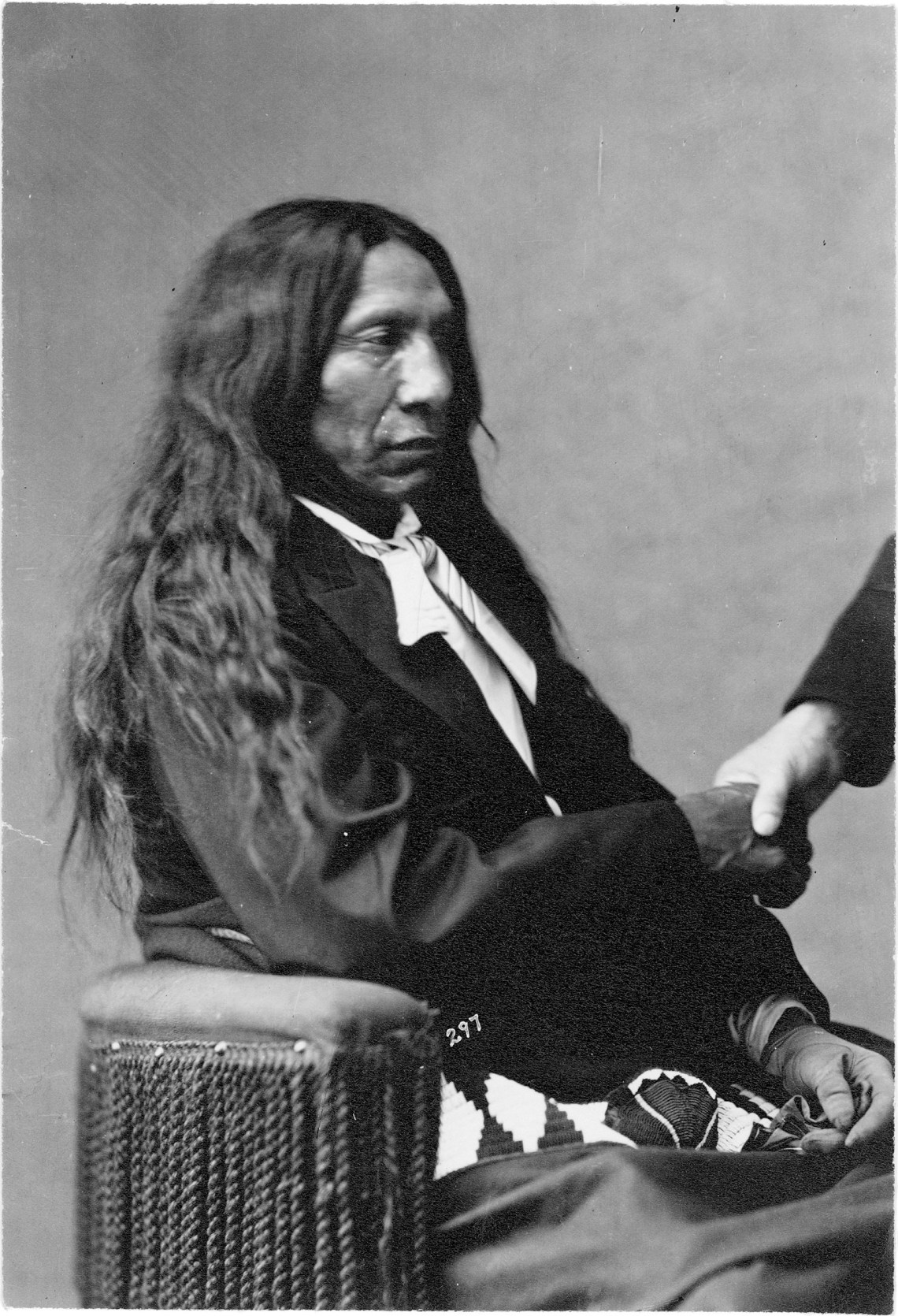 Oglala Lakota Chief Red Cloud in a formal portrait arranged by William Blackmore, whose hand is visible at right