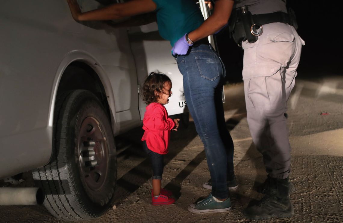 A two-year-old Honduran asylum-seeker crying as her mother is searched and detained near the US-Mexico border