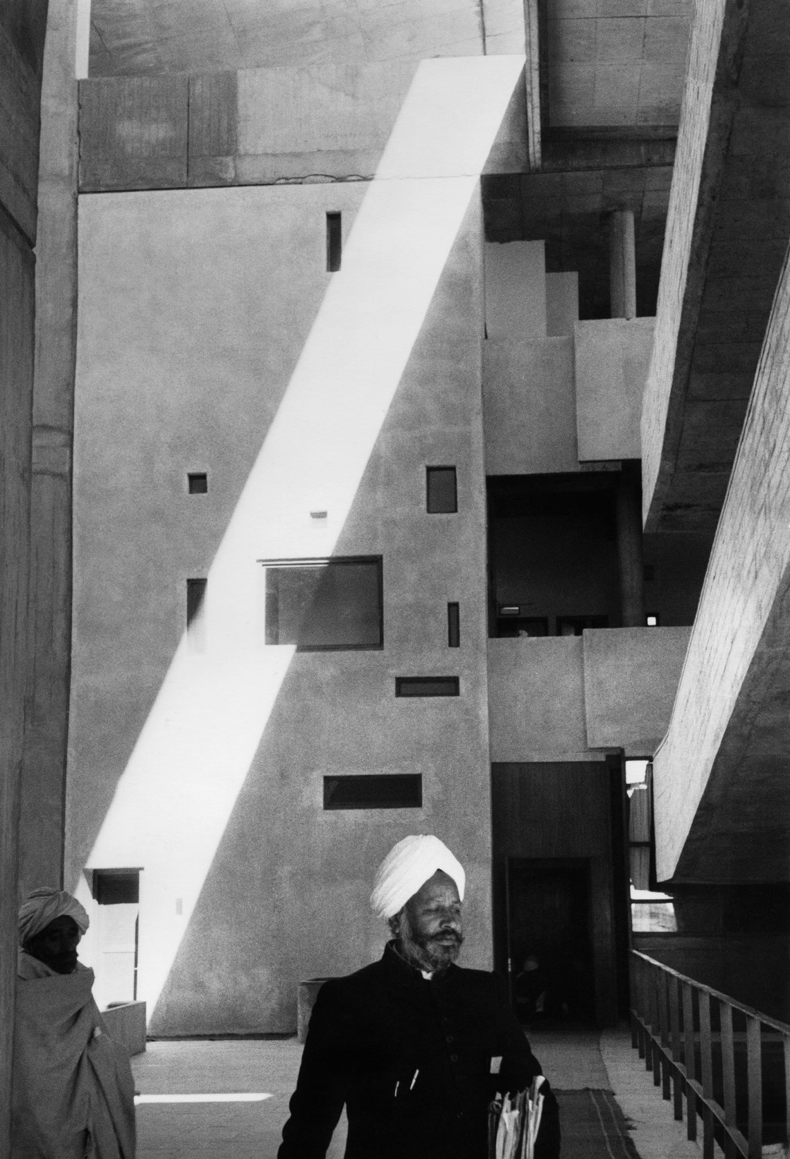 black and white shadows and geometries of the buildings in Chandigarh, with two figures include a man in a turban walking toward the camera