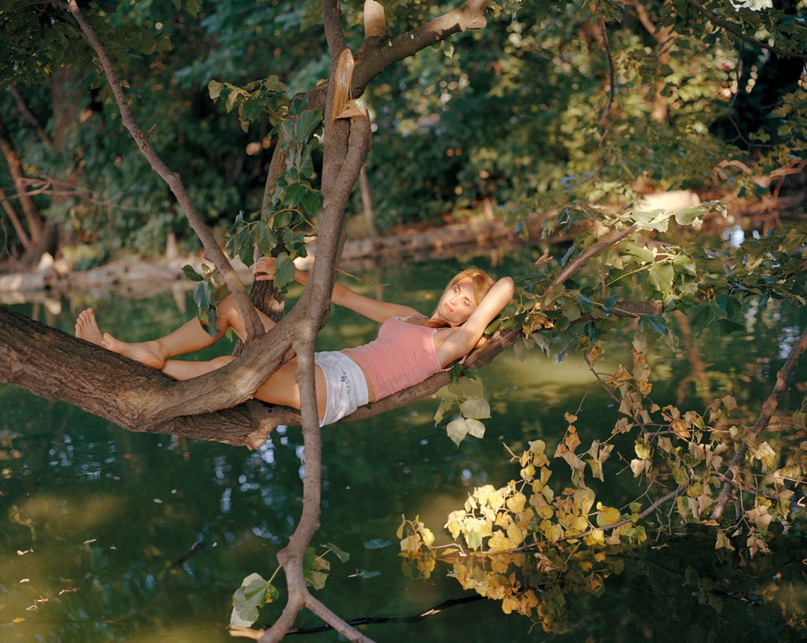 woman lying on a tree branch over water