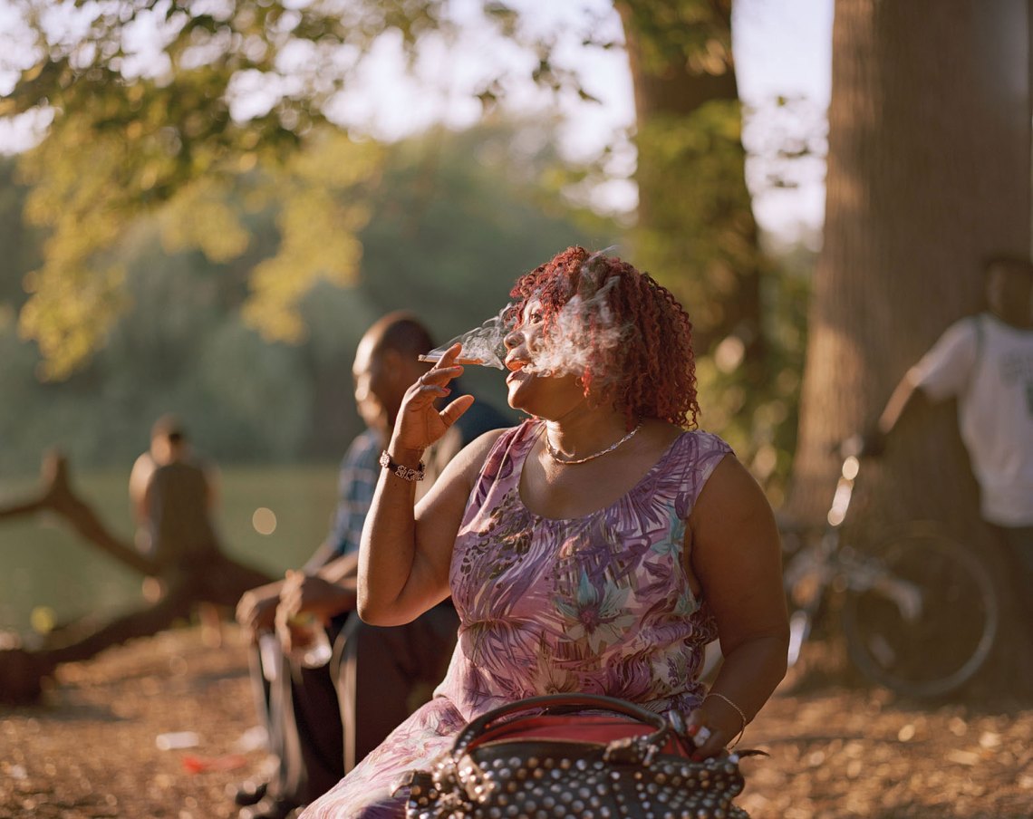 African American woman smoking with the sun against her, everything washed in golden light