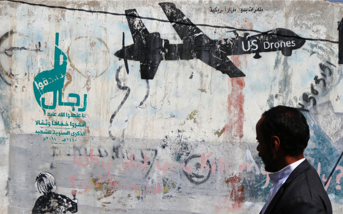 A man passing a wall with graffiti in Sana’a, Yemen
