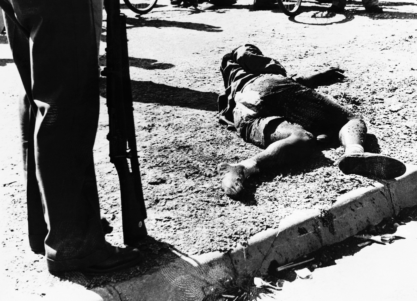 A police officer standing over a victim of the Sharpeville Massacre