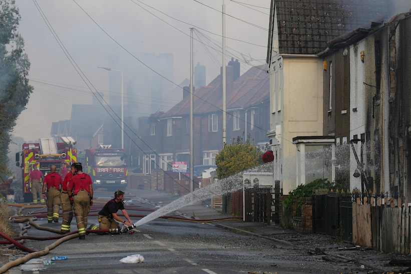 Firefighters douse homes set ablaze by grass fires during the heatwave in Wennington, east London