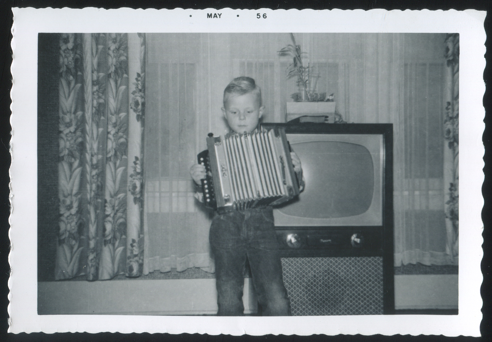 Young boy with accordion in front of TV set