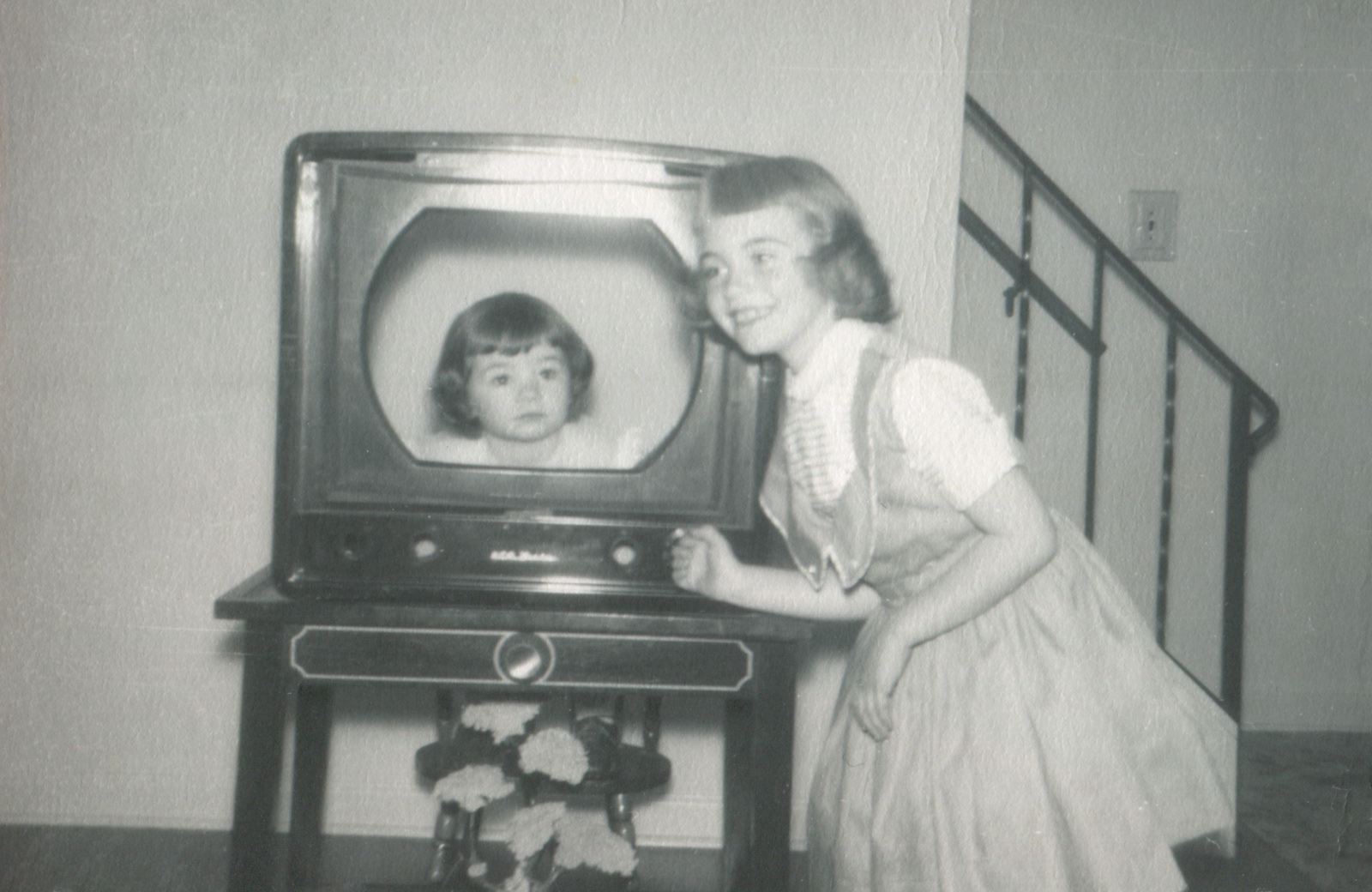 Young girl posing with younger girl in a hollowed-out TV set