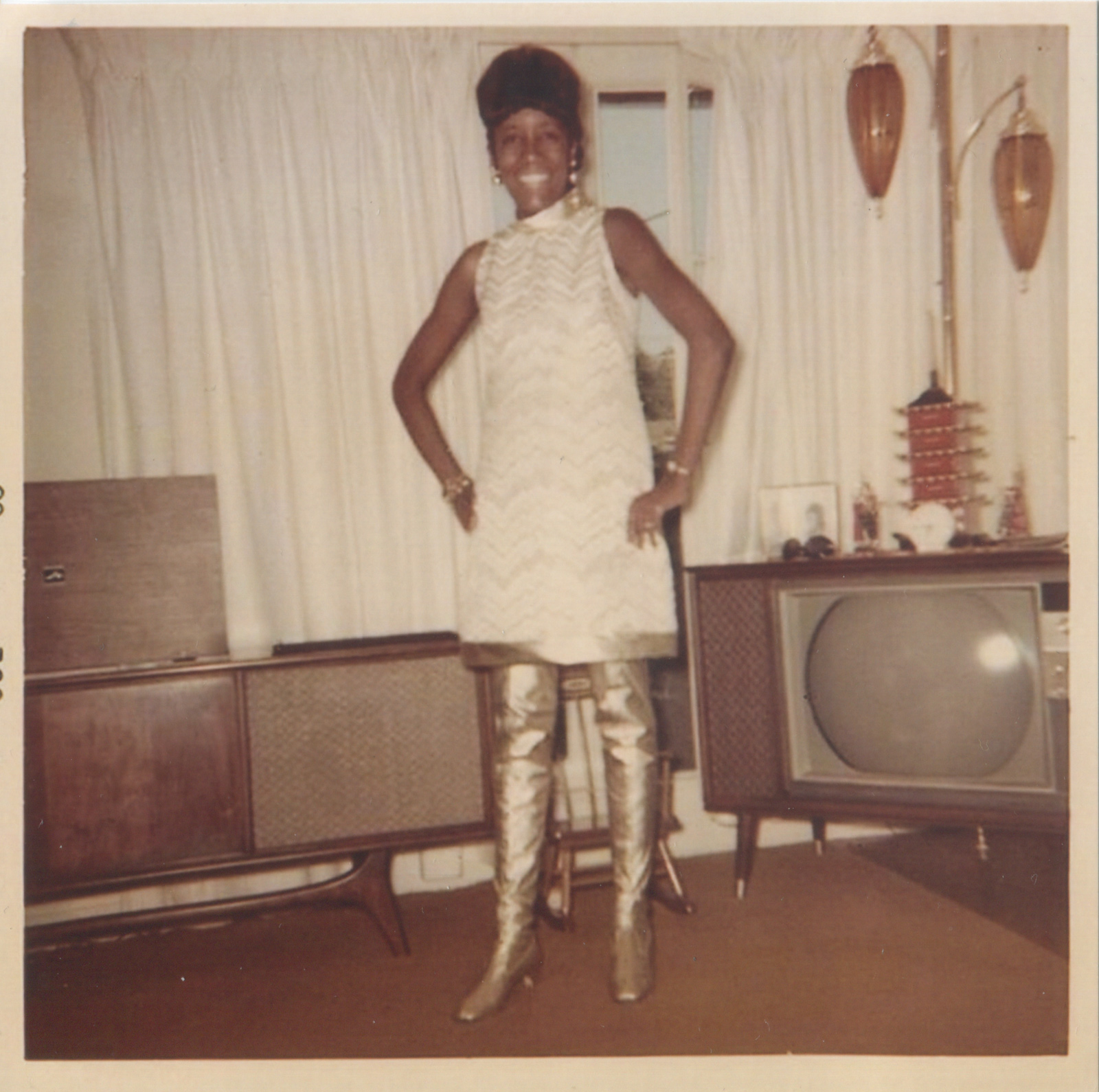 Woman posing with knee-high silver boots in front of TV set