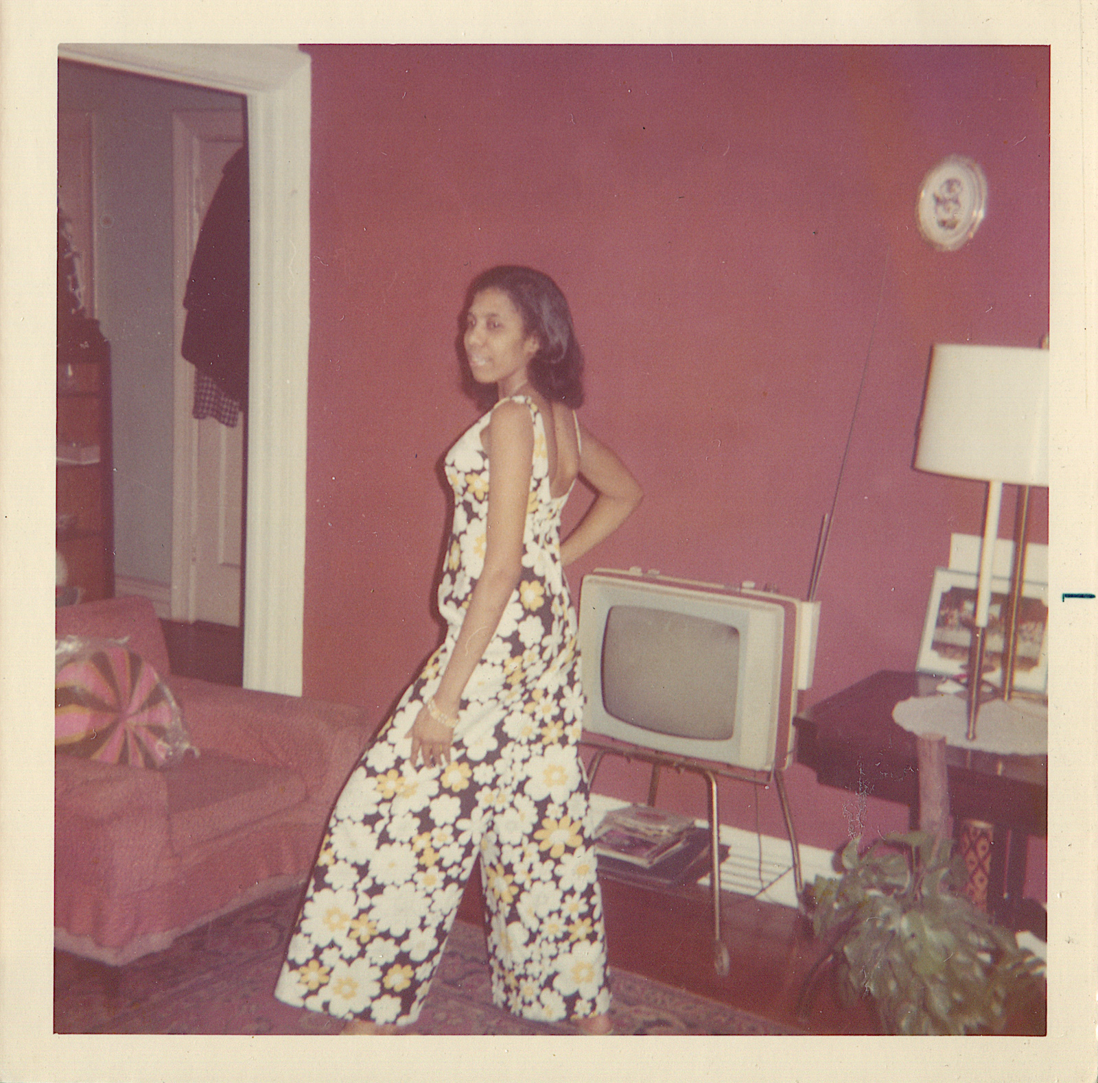 Woman in floral jumpsuit posing in front of TV
