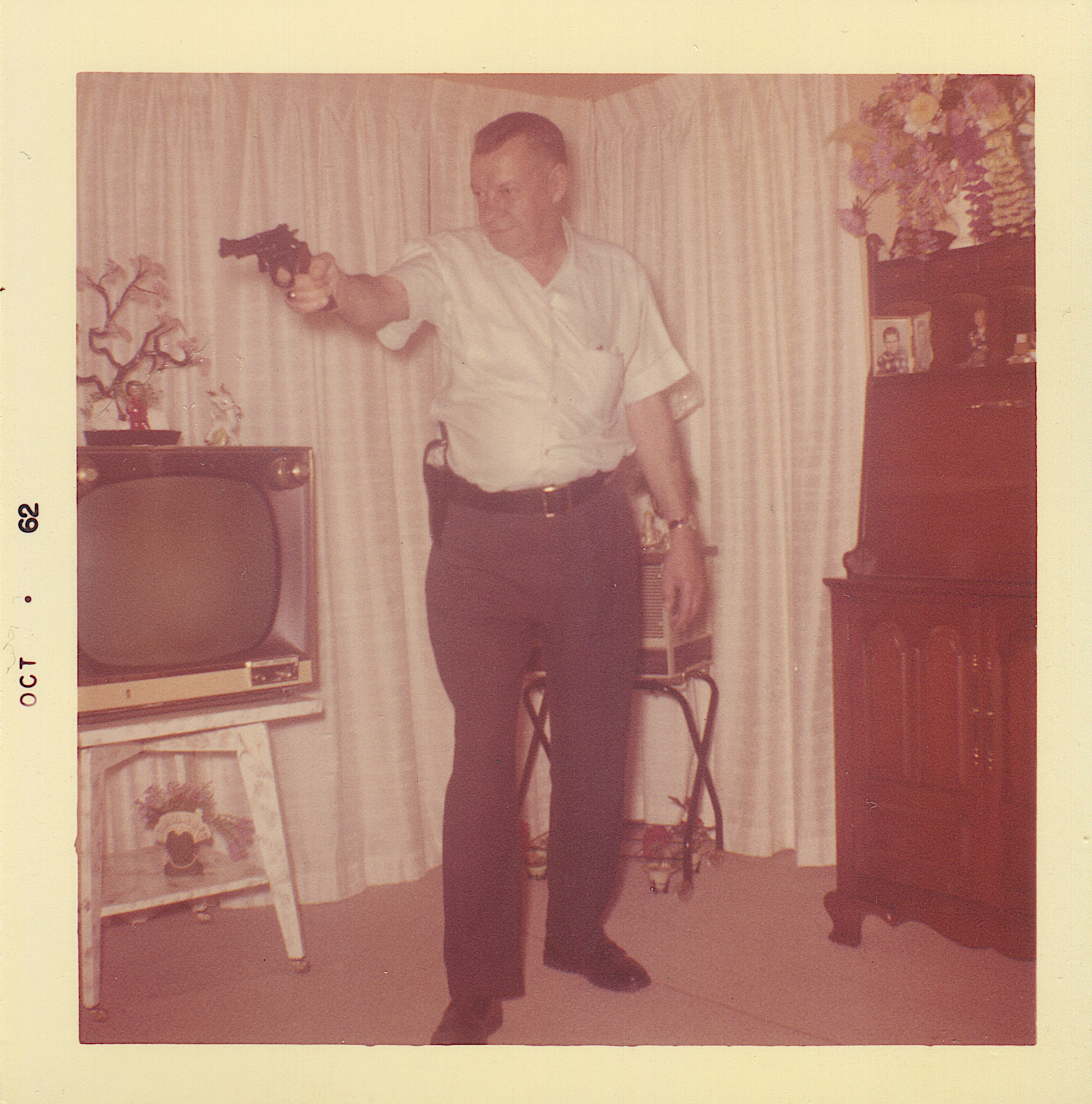 Man with pistol in front of a TV set