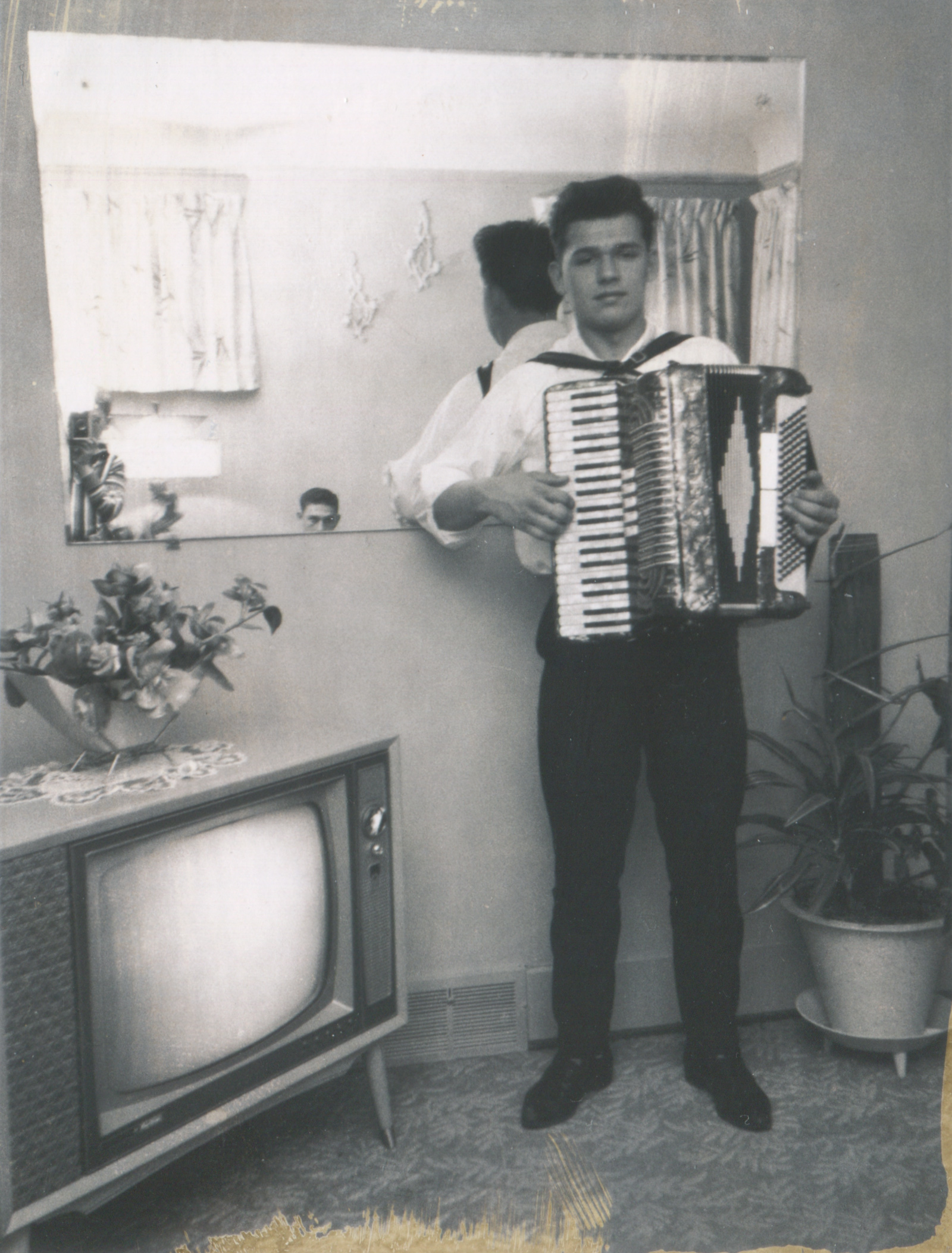 Man with accordion next to a TV set